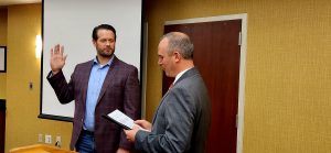 Two men standing in suits swearing into oath