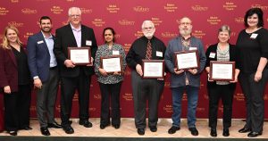 SU faculty standing in a line holding awards