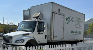 Large white donation truck beside a picket fence