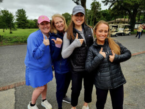 Group of girls dressed for golf holding up the thumbs up sign