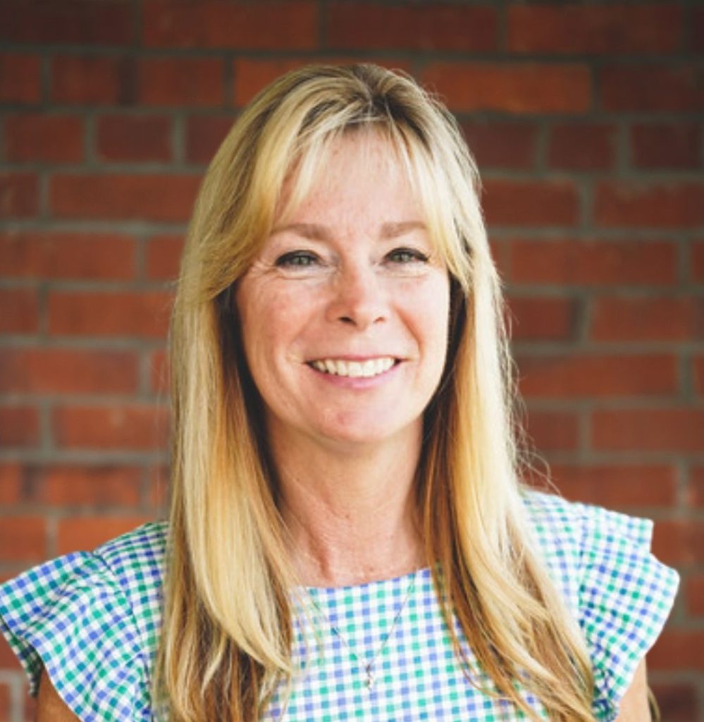 Headshot of a blonde women against a brick wall