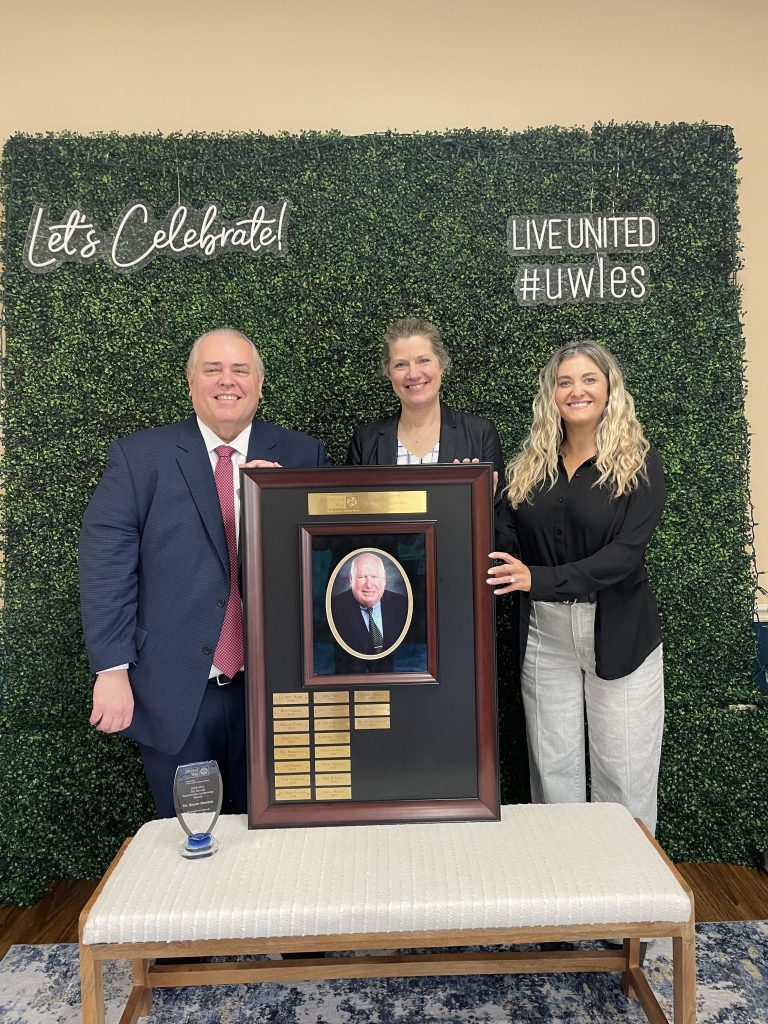 Three people holding a large award