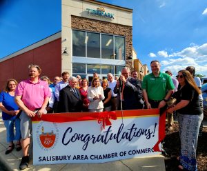 Large group of people holding a banner for ribbon cutting