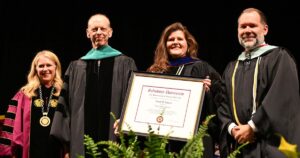 Four people on a stage at a graduation