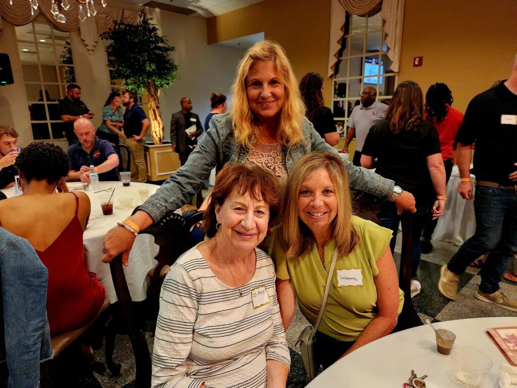 Three smiling women sitting at a table at an event