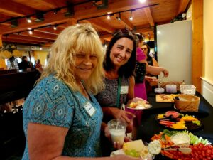 Two smiling women at a buffet table