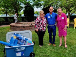 Group of three people standing next to a cooler full of gifts