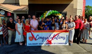 Large group of people holding a banner for a ribbon cutting