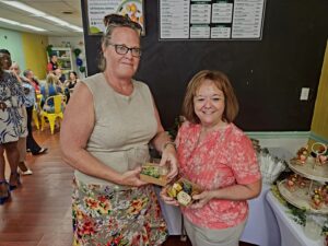 two adult females standing together holding fruit