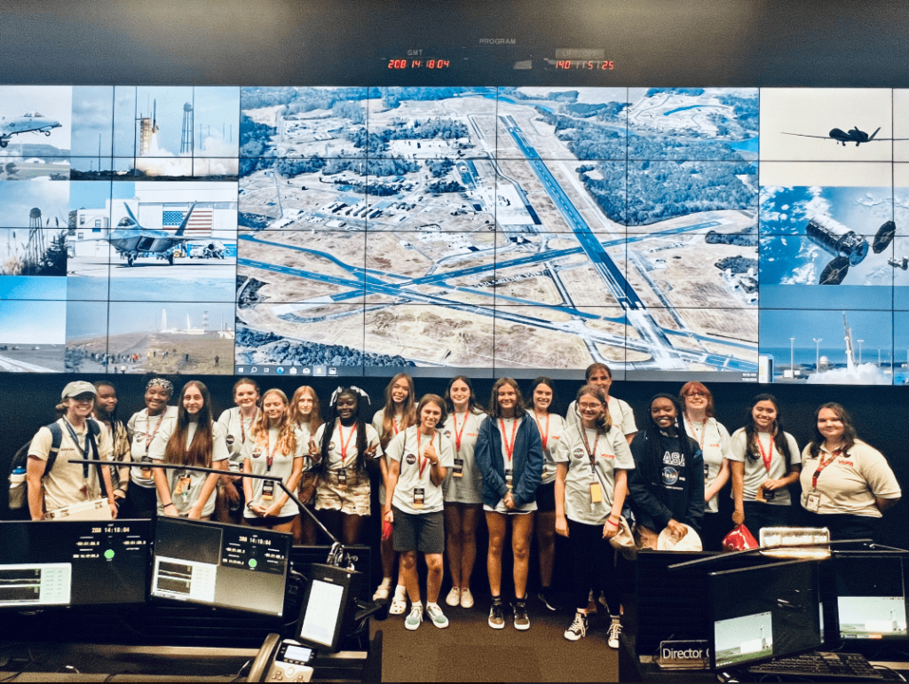 Space campers standing in front of a big screen 