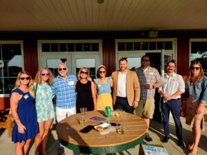 Large group of smiling people outside behind a table