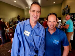 Two men with blue shirts smiling for the camera