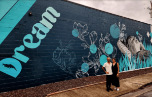 Two people standing in front of a mural