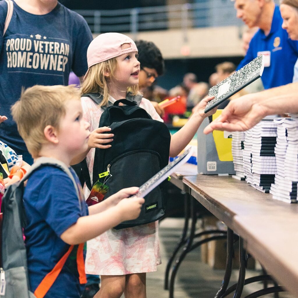 little kids being handed notebooks