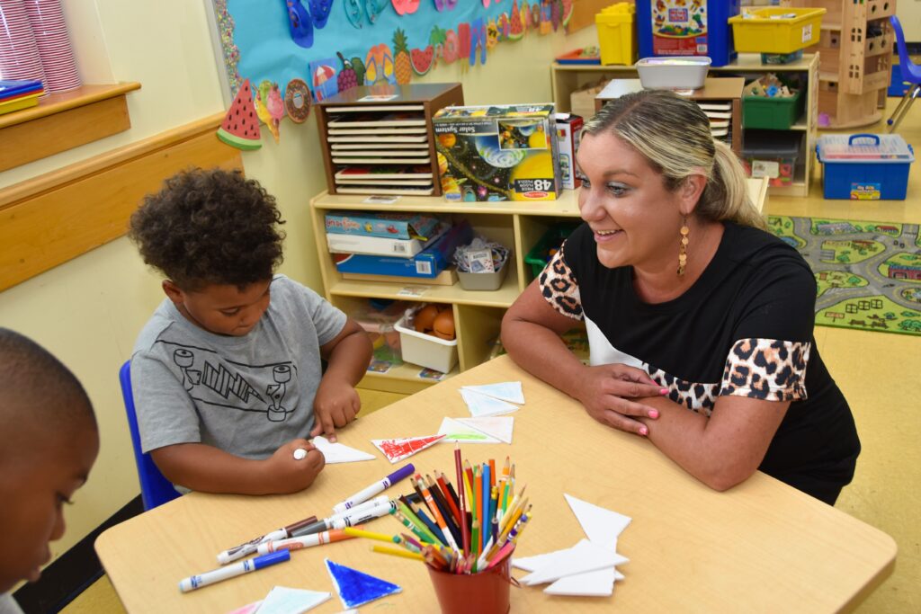 teacher working with a little boy to make a rocket