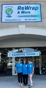 Three people standing outside of the new Rewrap store