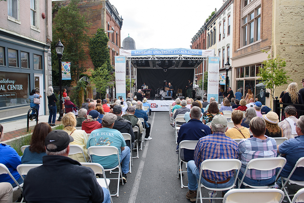 Stage on the street with people sitting in chairs to view the festival performances