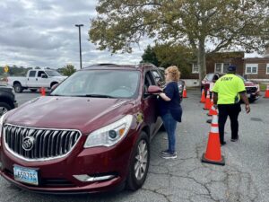 woman standing outside of a maroon vehicle at a drive thru flu shot clinic