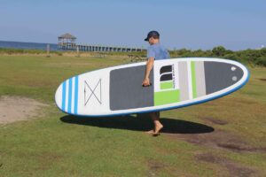 man carrying paddleboard to water