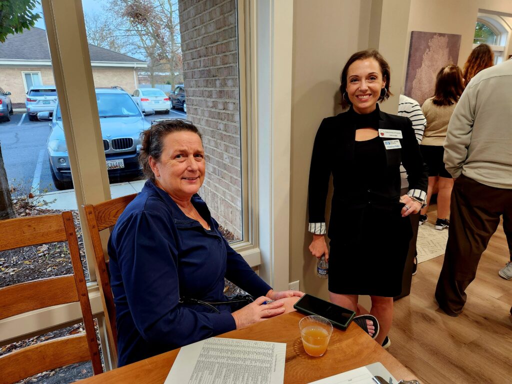 Two women one standing and the second sitting at a table