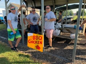 wiersberg-warriors-bbq three men standing by a bbq chicken sign