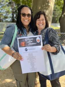 Welcome New Teachers two women smiling and holding a poster for welcome new teachers