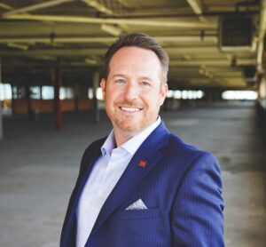 A man in a blue suit smiling for his portrait.