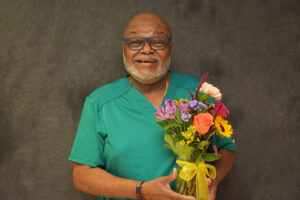 2025 August Sunshine Award | Jackson A man smiling for his picture with a bundle of flowers.