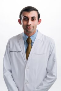 Ahmad Yousuf A man in a doctors jacket smiling for his portrait
