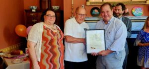 3 people holding a framed document.