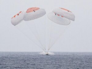 parachutes holding person in a body of water
