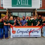 A group of individuals smiling with a congratulations banner.