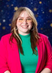 A woman in a red blazer smiling for her portrait.