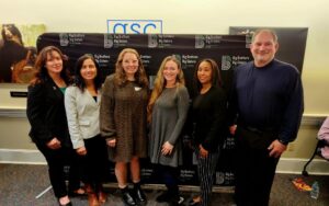 Directors standing in front of Big Brother Big Sisters sign.