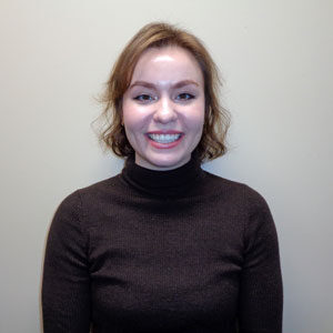 A women with short hair in a brown turtleneck.