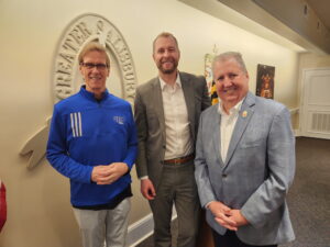 Three men standing and smiling.