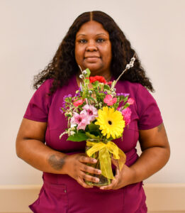 A women wearing scrubs holding flowers.